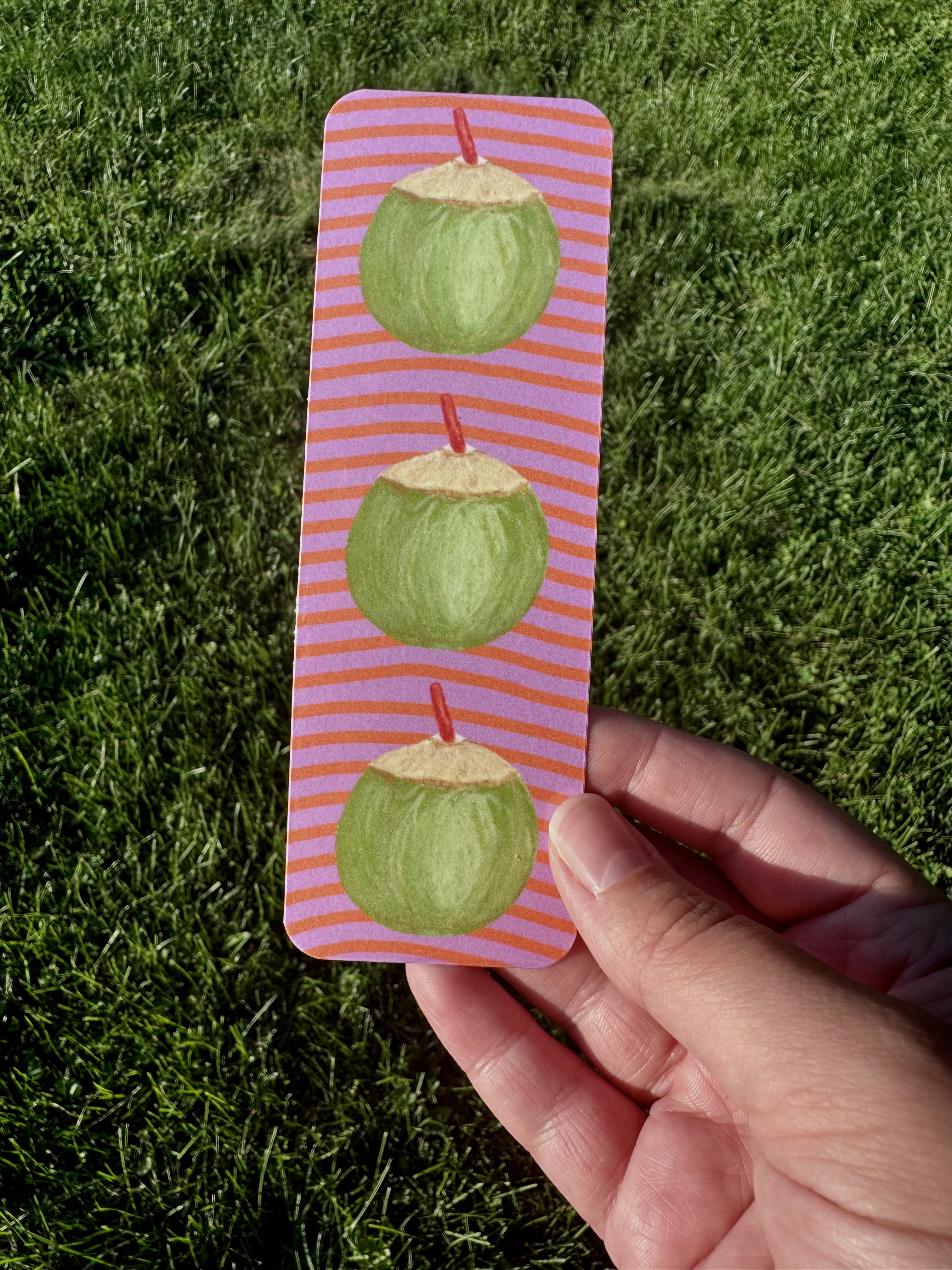 Coconut bookmark with three green coconuts and red straws on lavender and coral stripe background