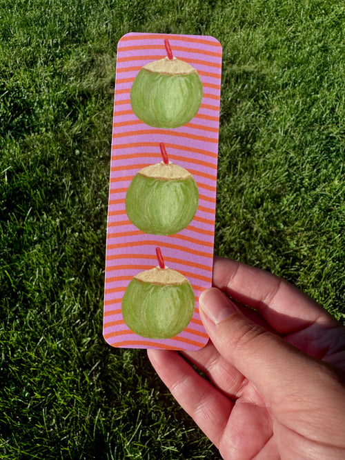 Coconut bookmark with three green coconuts and red straws on lavender and coral stripe background