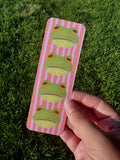 Frog bookmark with four round green frogs with golden eyes on pink and lavender stripe background