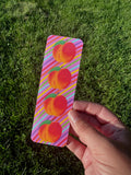 Peach bookmark with three orange peaches and green leaves on multicolor diagonal stripe background